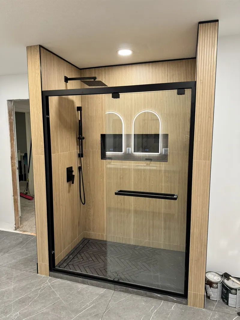 Walk-in shower with black-framed glass door and oak-look tile