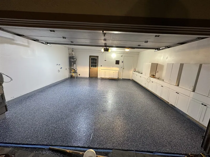 Garage with white cabinets along the wall and a grey flake epoxy floor