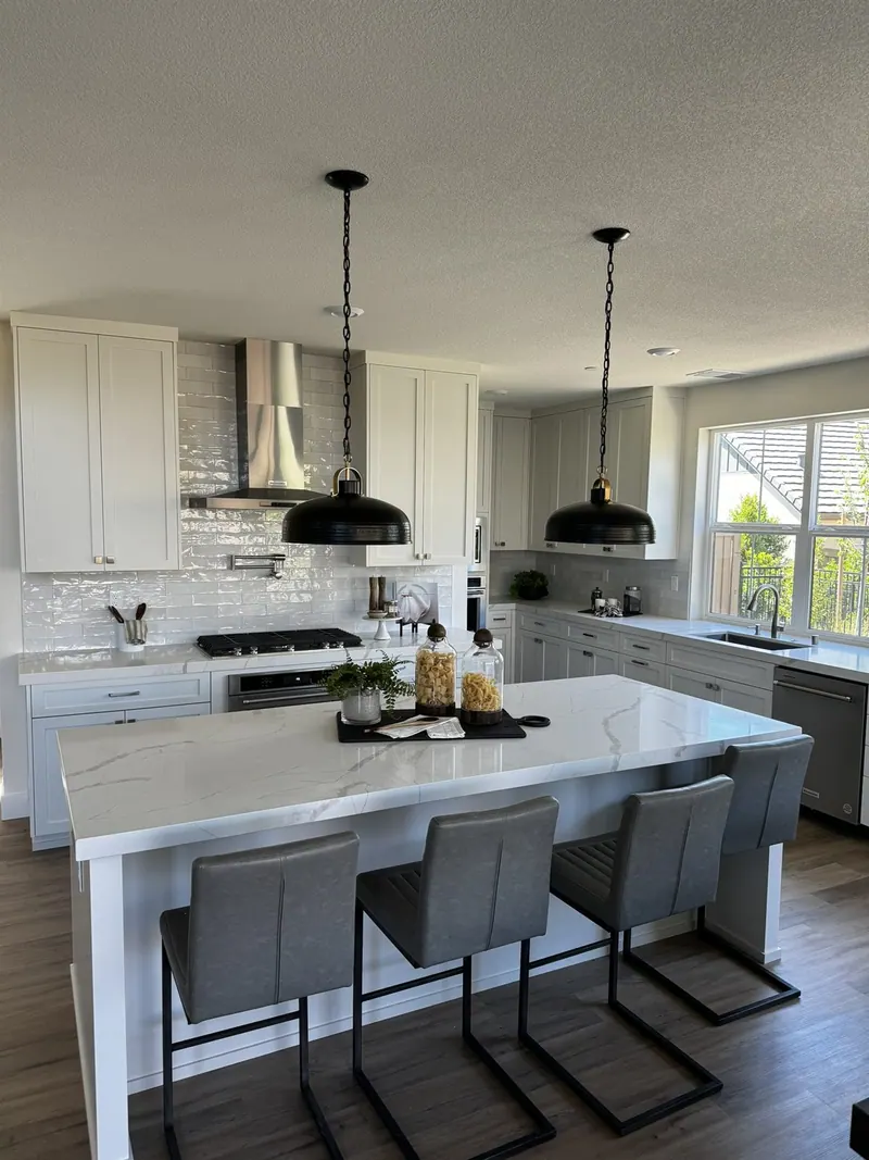 White kitchen island with bar seating and black pendant lights